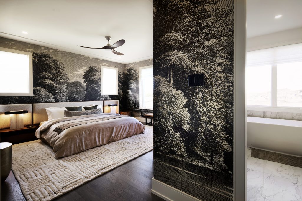 The Stonehaven Loft model home: bedroom with a forest-print feature wall and ceiling fan
