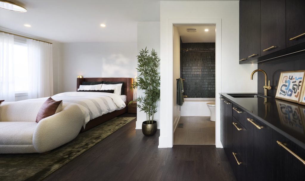 The Stonehaven Loft model home: bedroom with a dark dressing wall and ensuite beyond