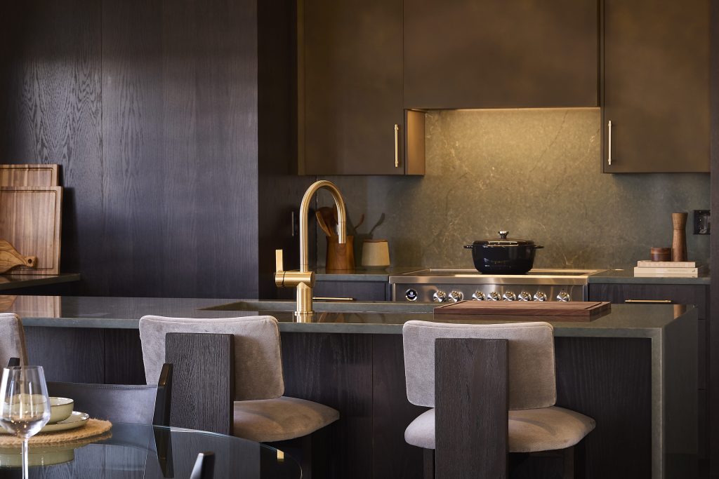 The Stonehaven Loft model home: kitchen with dark cabinetry, a brass tap and island seating