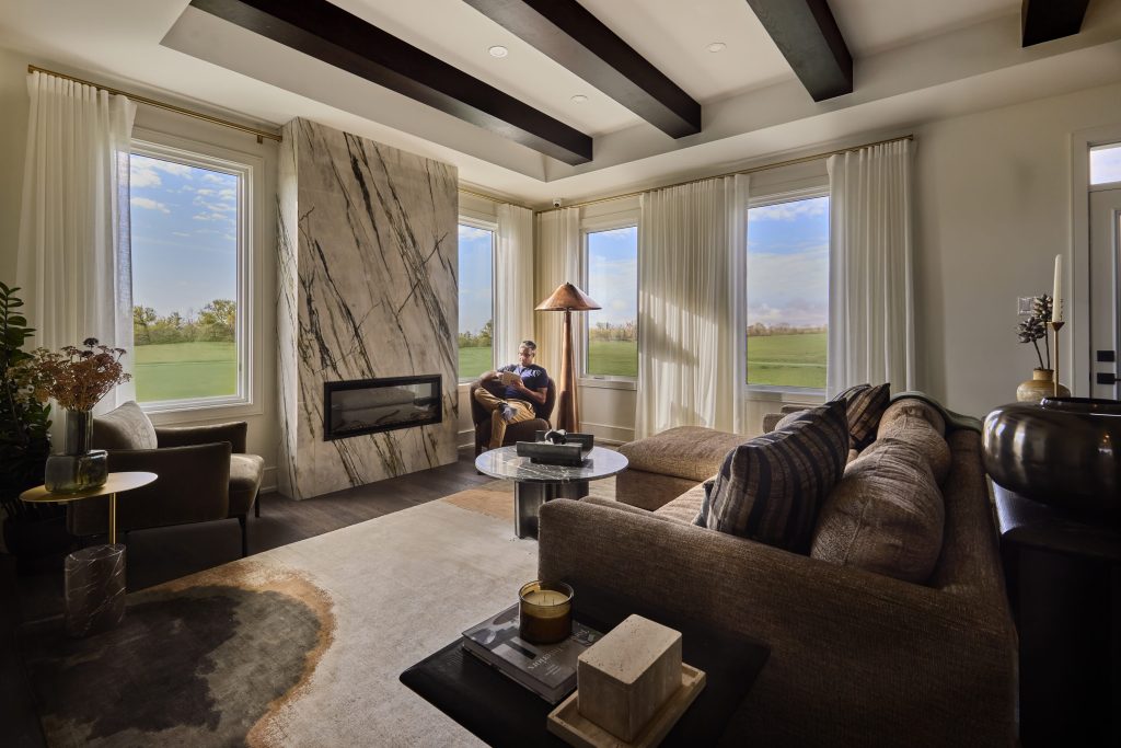 The Stonehaven Loft model home: living room with a linear fireplace and beamed ceiling