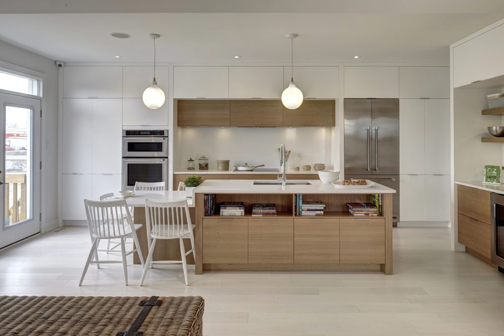 Series II Plan 2 model home: white kitchen with an island, pendant lights and a dining table