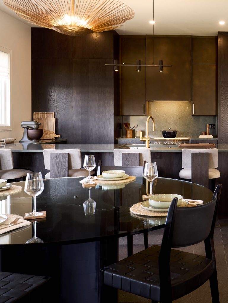The Stonehaven Loft model home: dining table beside the kitchen, under a woven pendant