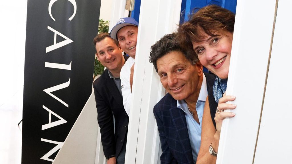 Four guests at the Blue Door Gala launch, beside a Caivan banner