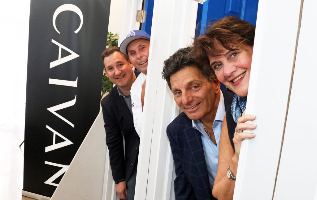 Four guests at the Blue Door Gala launch, beside a Caivan banner