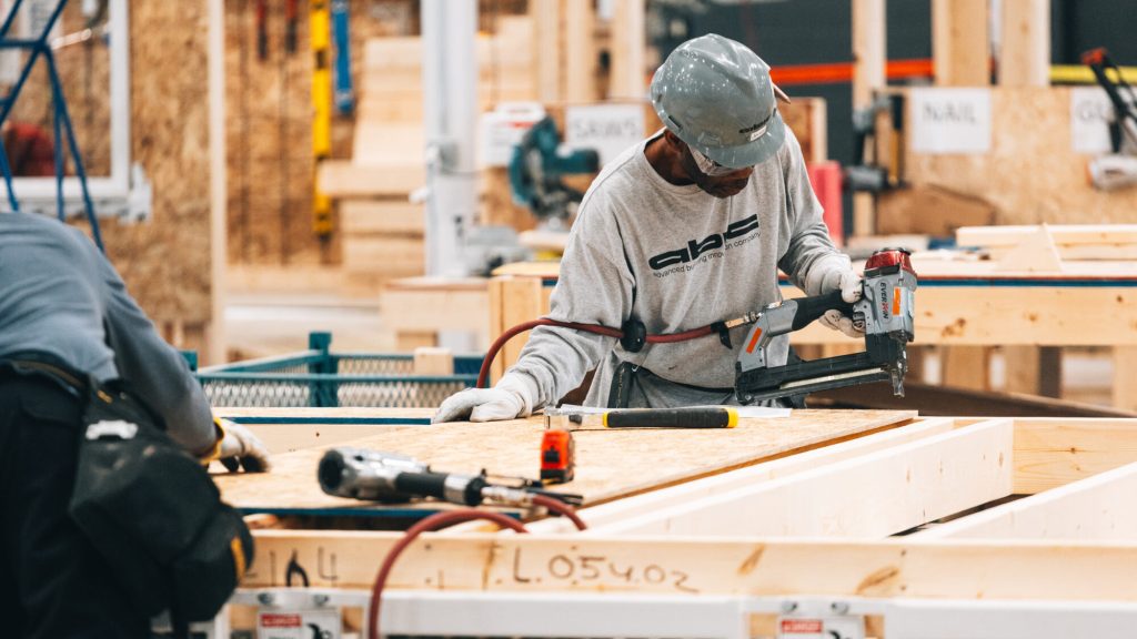 A worker assembling a timber wall panel on the factory floor