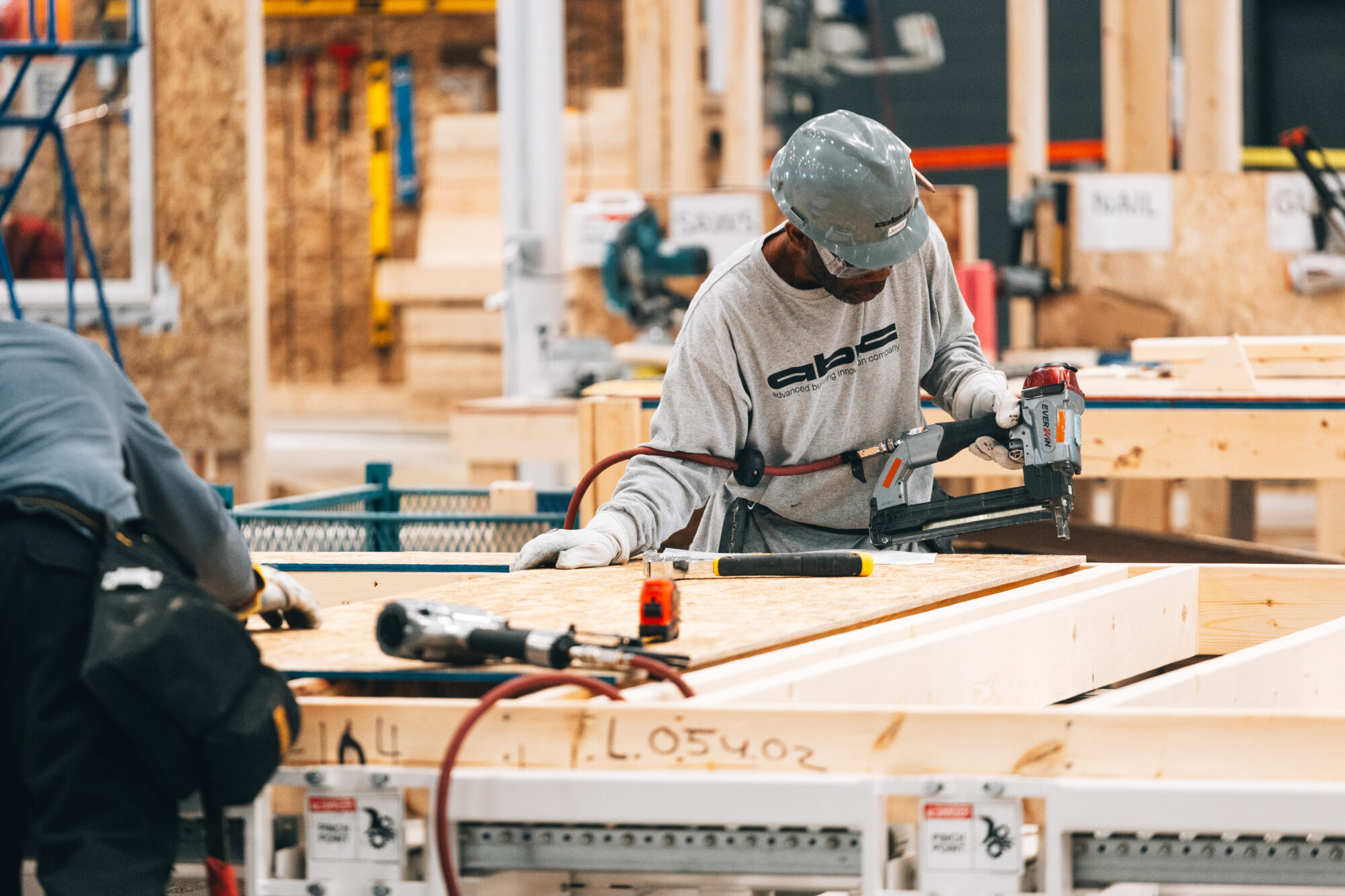 A worker assembling a timber wall panel on the factory floor