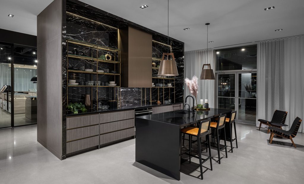 Design Studio kitchen display, with dark marble cabinetry, an island and bar stools