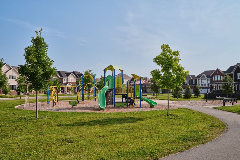 A playground and lawn at The Conservancy, with homes along the far side