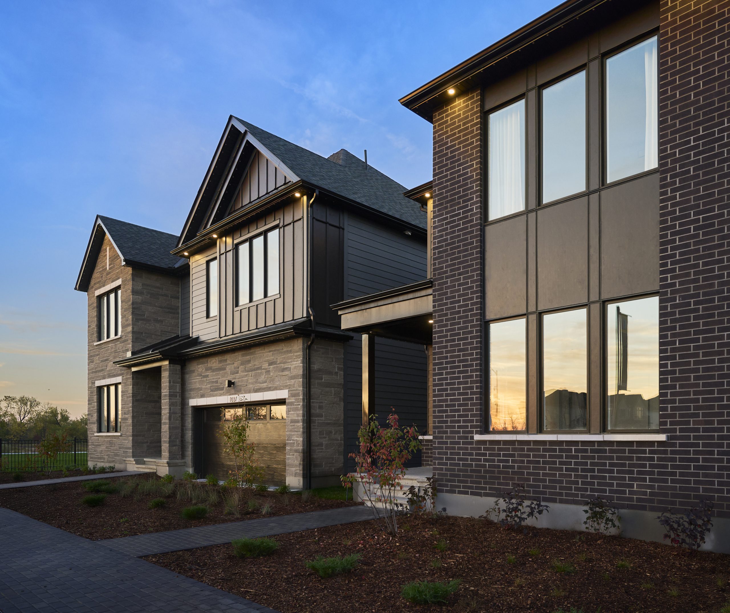 Exterior of a Caivan home at The Conservancy at dusk, in stone and dark siding