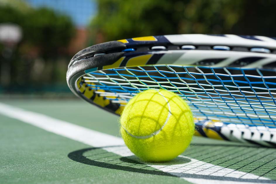A tennis racket and ball on a court baseline