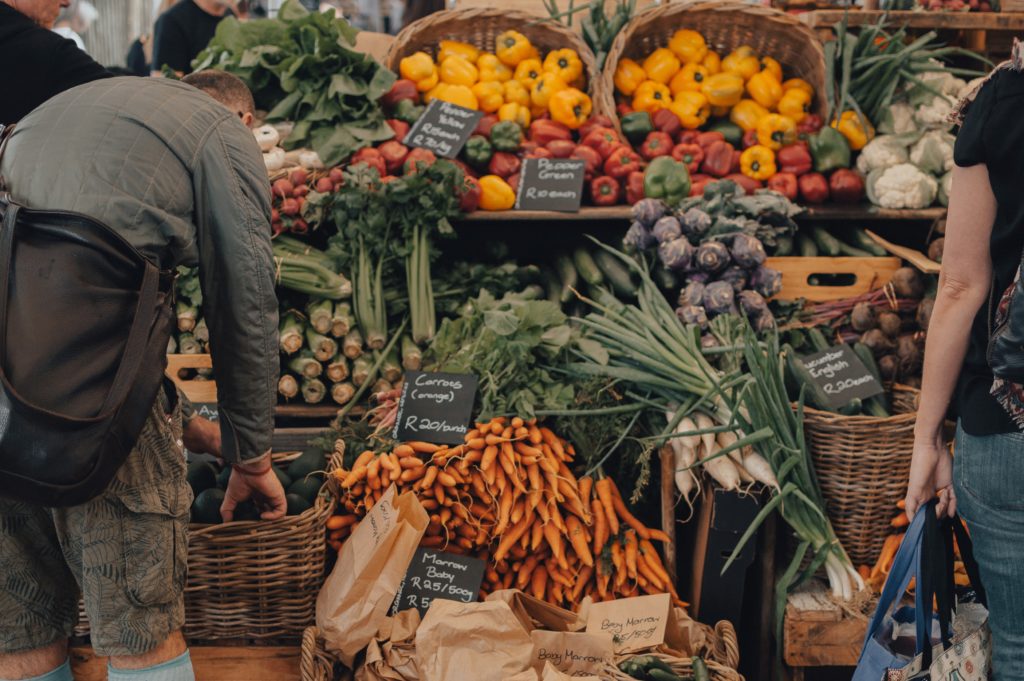 A shopper at a farm stand stacked with vegetables