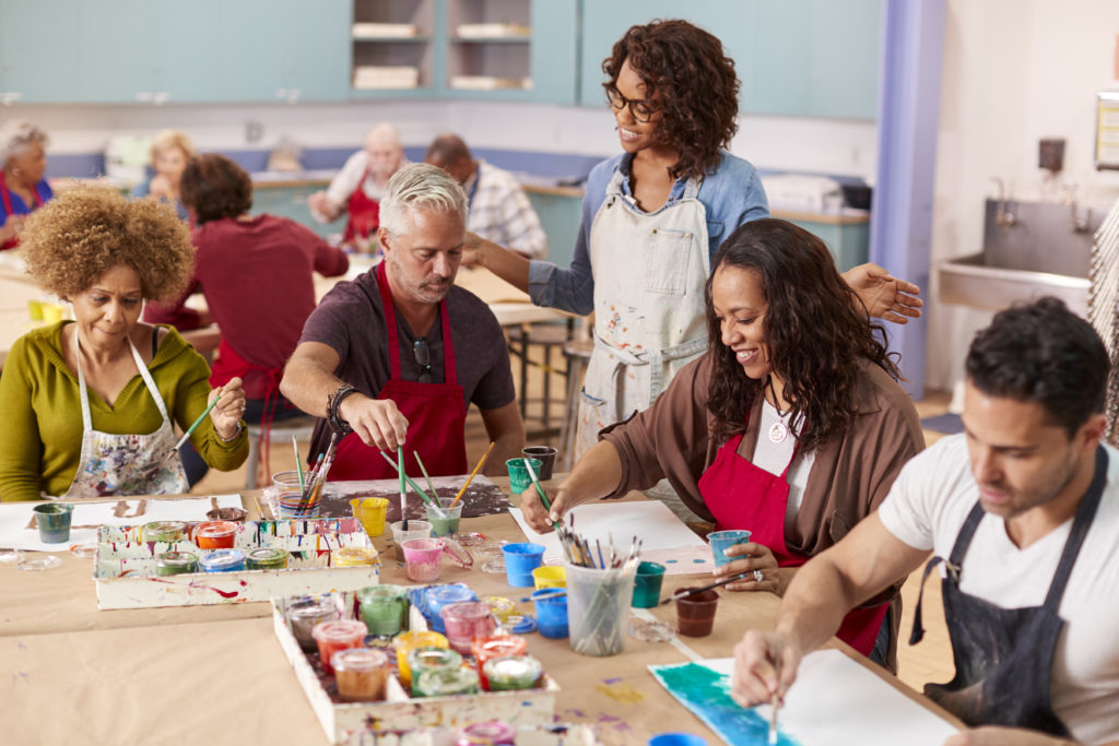 A group at an art class working on paintings around a table