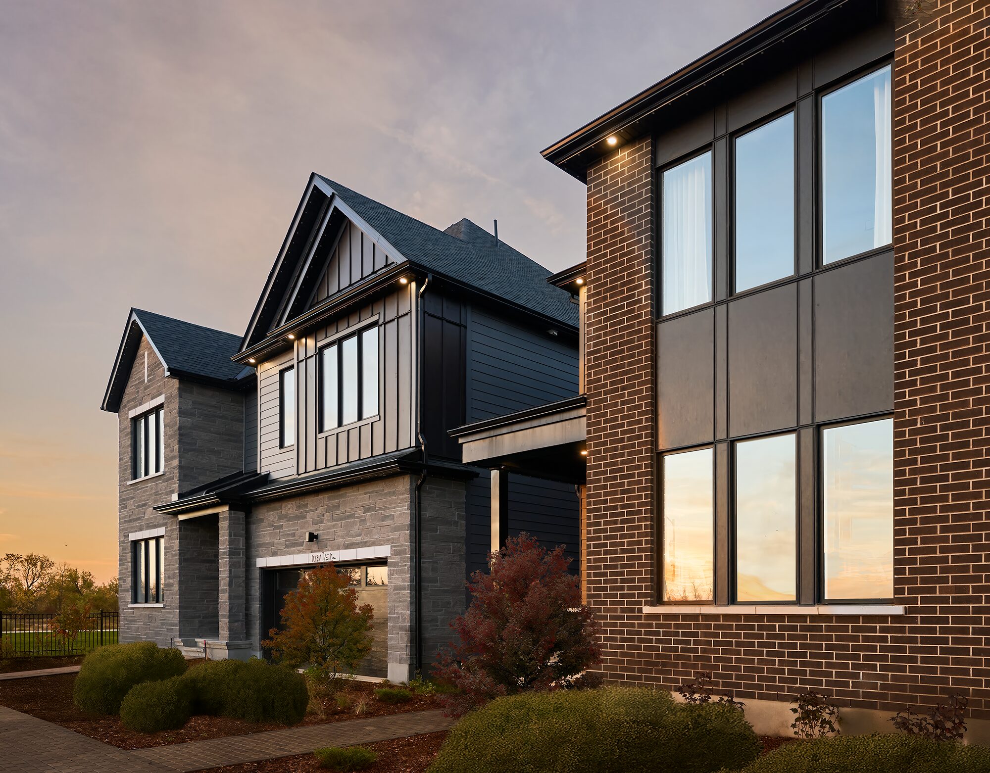 Exterior of a Caivan model home in brick and dark siding at dusk