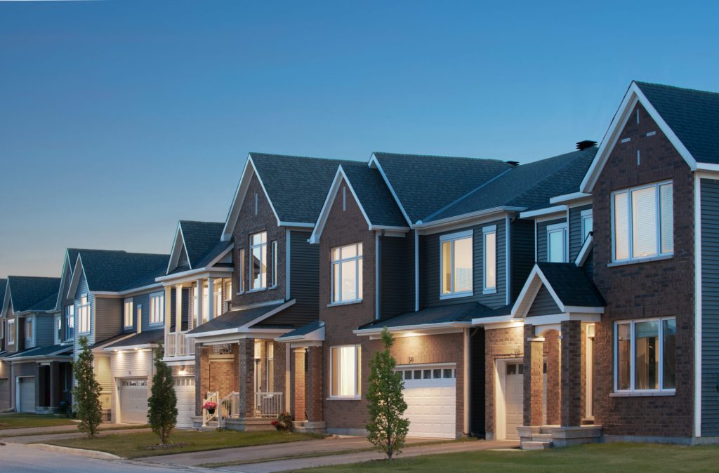 Street entrance to Orléans Village at dusk, with homes in brick and grey siding