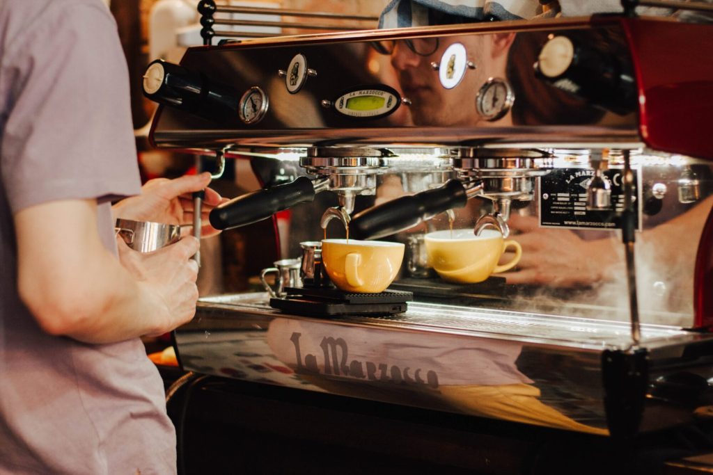 A barista pulling espresso into two cups