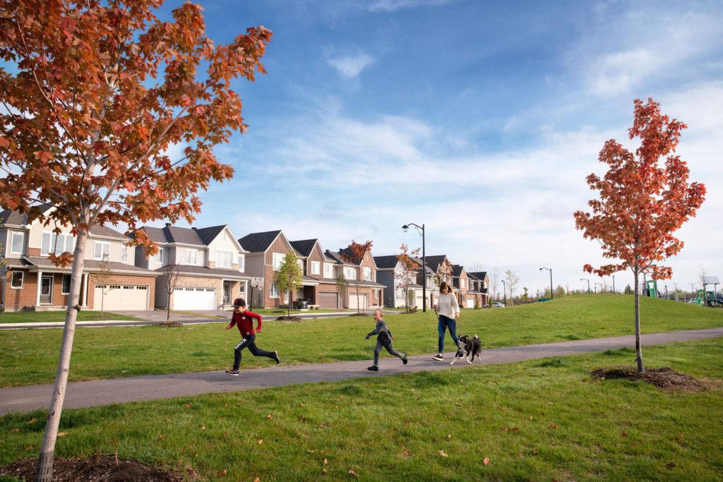 Children playing on the grass beside a row of Orléans Village towns in autumn
