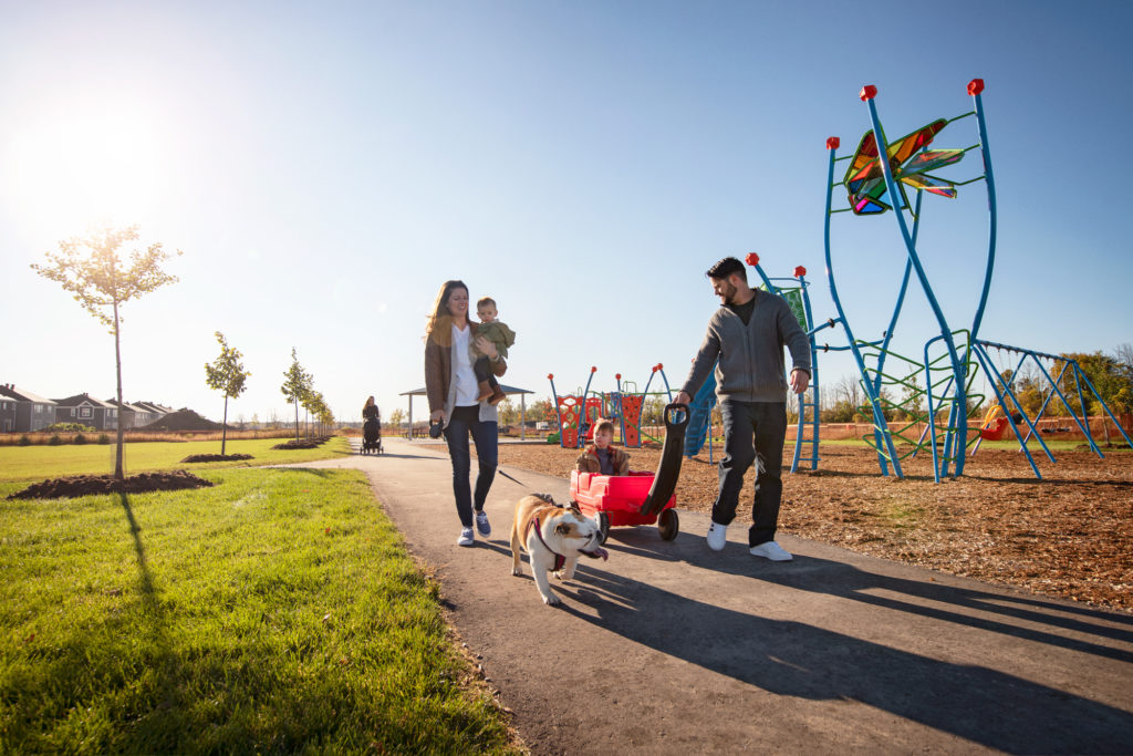 Families walking past a playground climbing frame at Fox Run