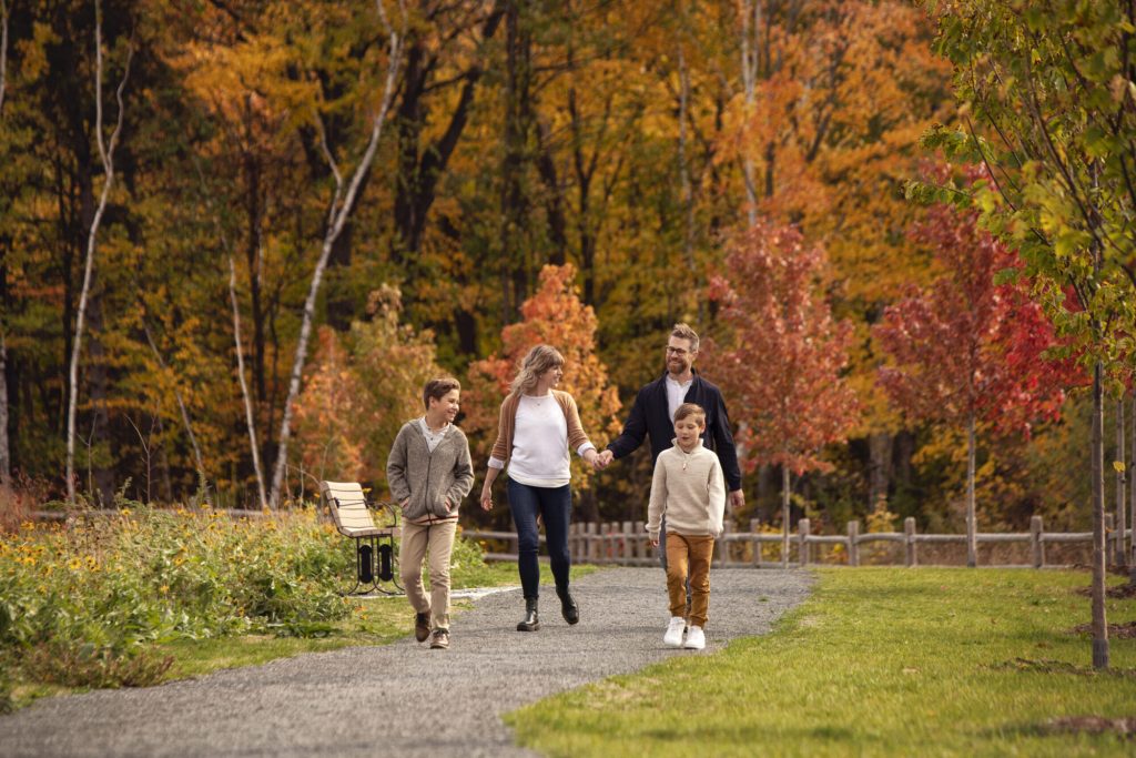 A family walking a park path through autumn trees