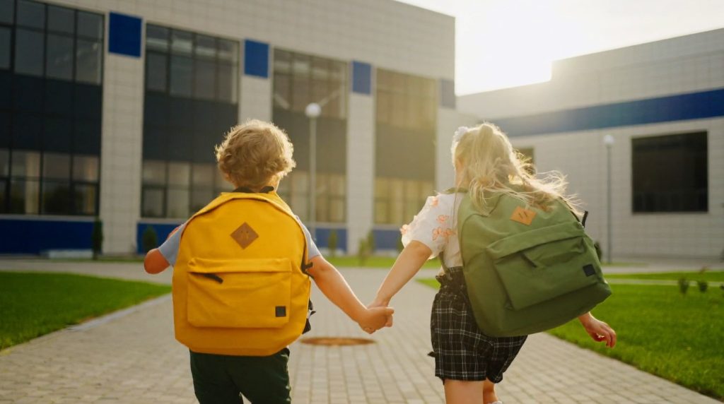 Two children running towards a school entrance