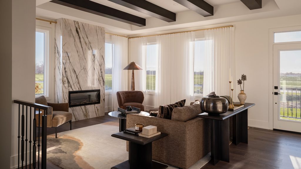 The Stonehaven Loft model home: living room with a stone fireplace and exposed ceiling beams