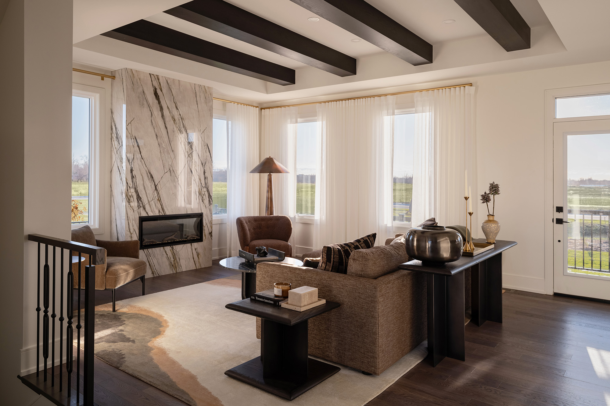 The Stonehaven Loft model home: living room with a stone fireplace and exposed ceiling beams