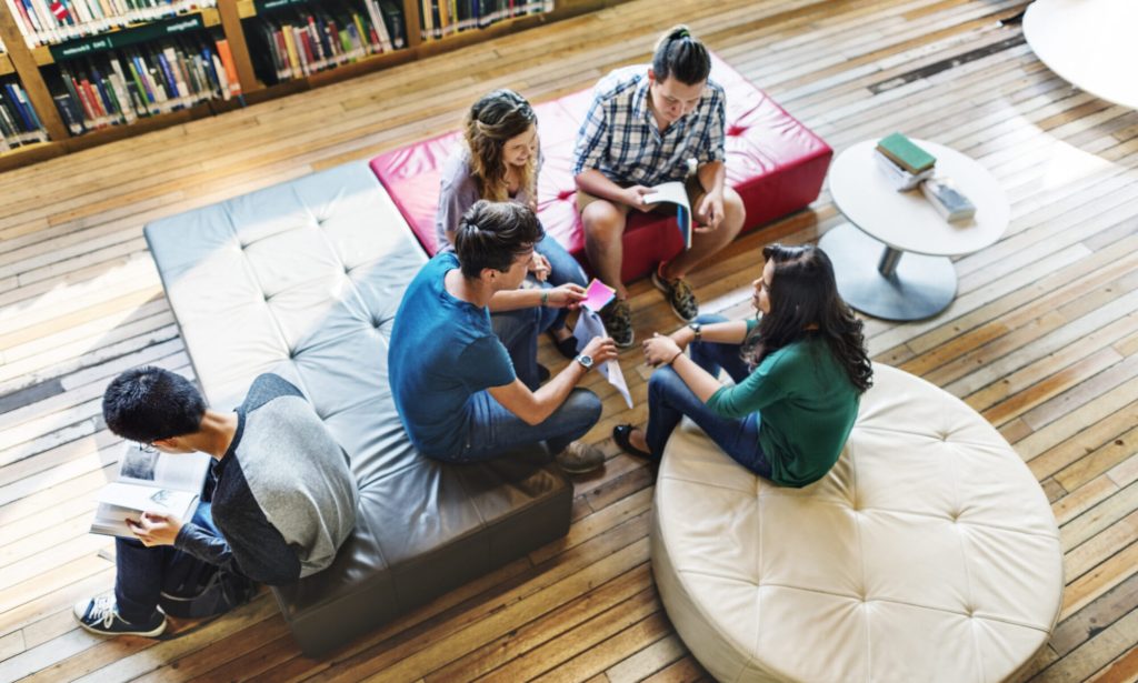 Students studying together on floor cushions in a library